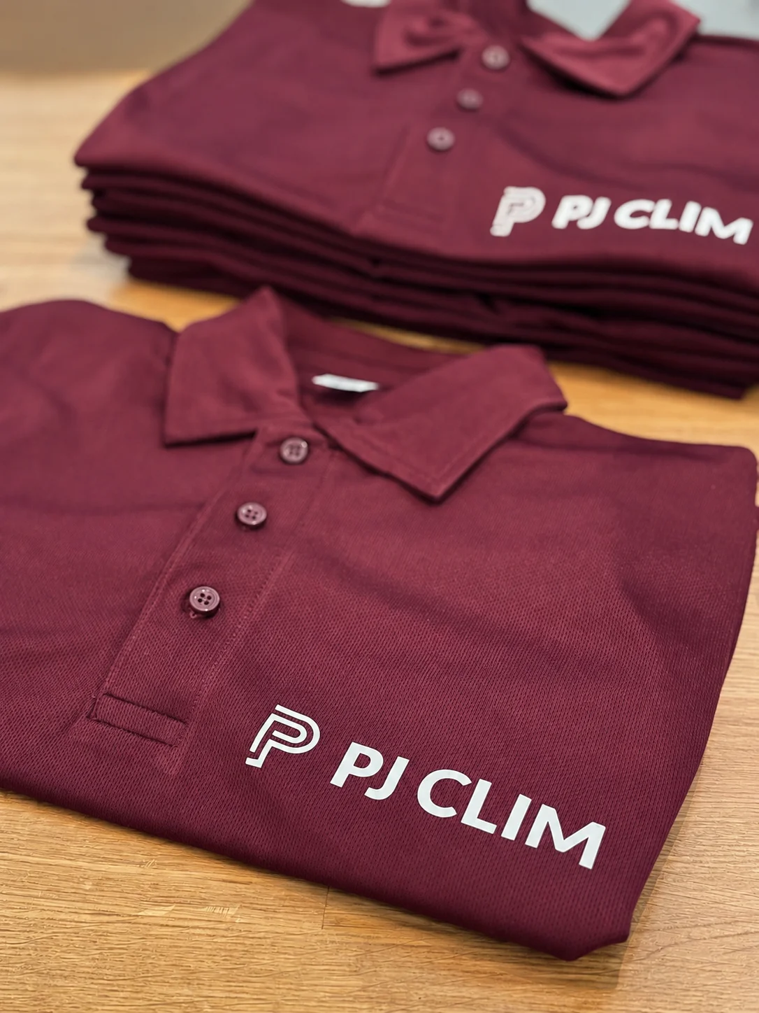 Flocage logo PJ Clim sur polos bordeaux empilés